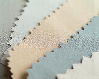 Close-up of colour and material samples including fabrics and wallpapers in natural tones